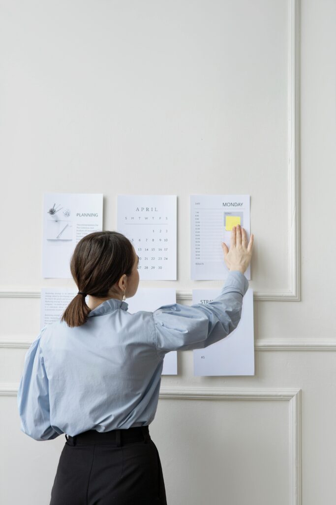 pexels-photo-7550893-7550893 Woman organizing wall planner in office showing strategy and planning.