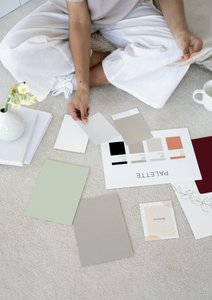 pexels-photo-7552373-7552373 Designer sits on carpet with color palettes and samples, planning creative project.